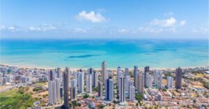 Vista aérea de empreendimentos imobiliários que unem arquitetura moderna, preservação ambiental e proximidade com o mar na Paraíba.